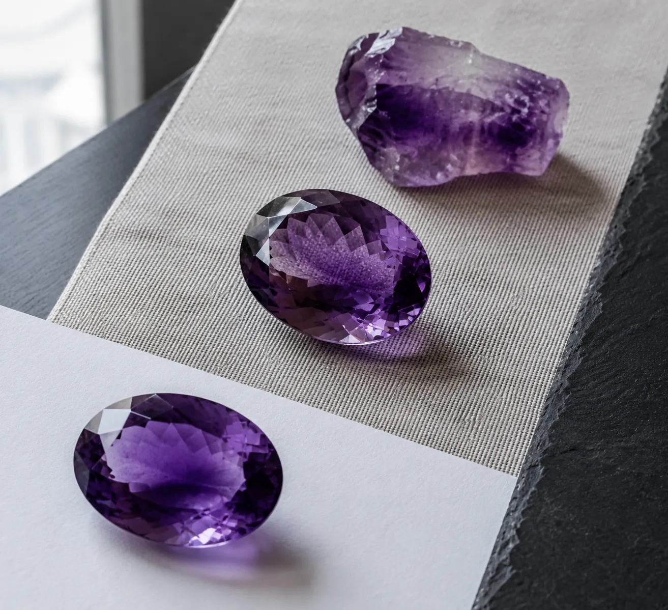 Loose amethyst on neutral surfaces showing how background and angle affect visible color zoning