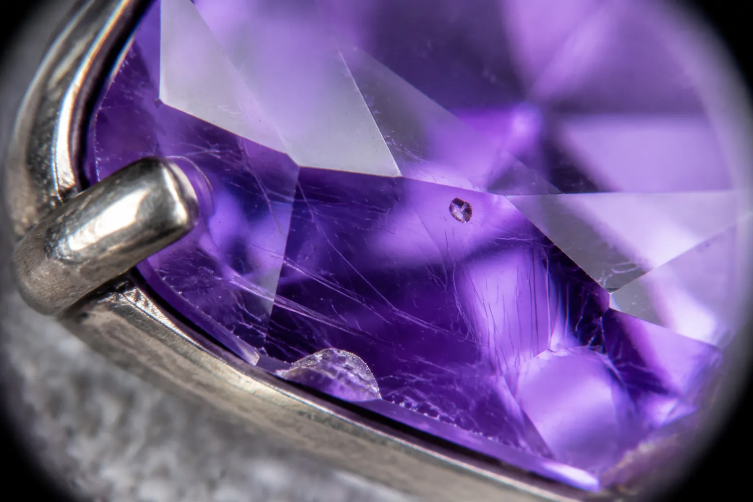 Close view of amethyst with internal lines and a jewelry setting showing possible stress paths